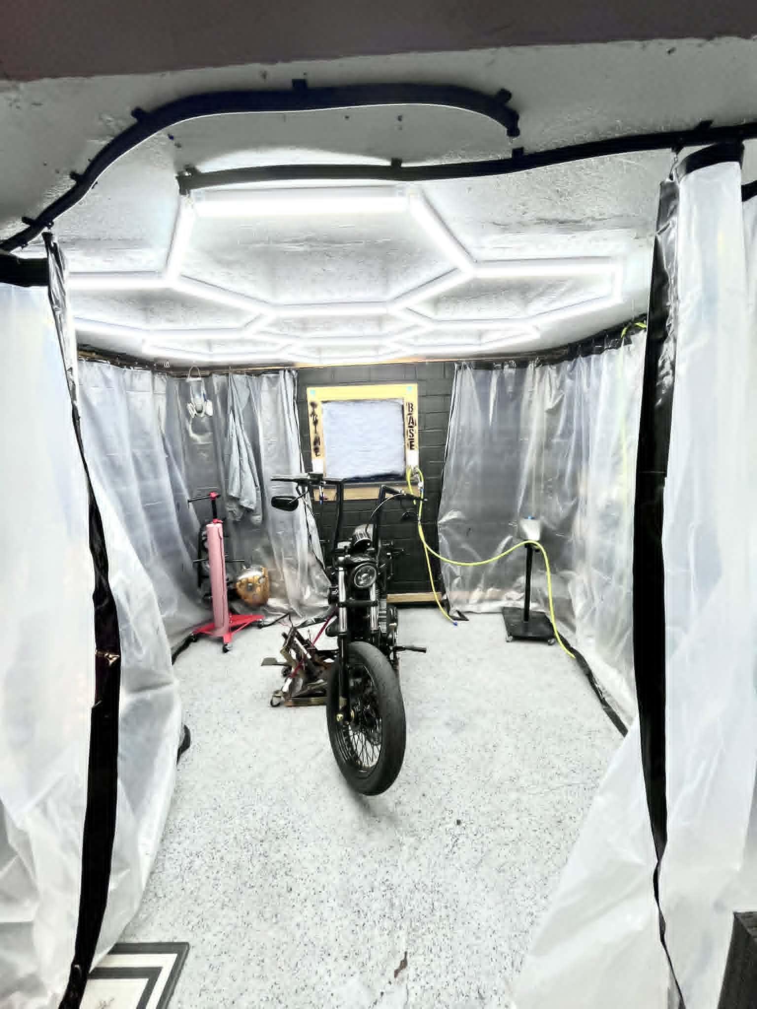 Iron Pony Customs paint booth — hex LED ceiling, plastic curtain walls, bike staged inside