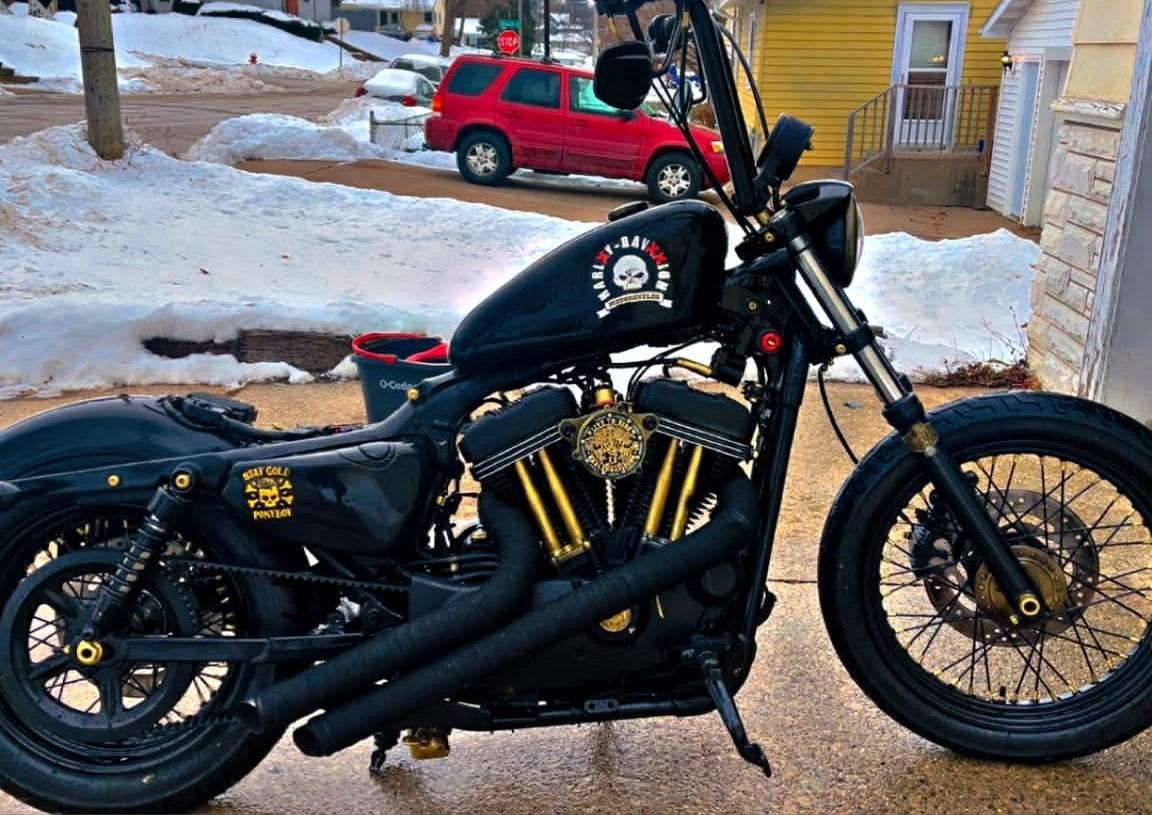 Black bobber Sportster outdoors with snow — Death Skull tank, gold engine accents, Stay Gold derby